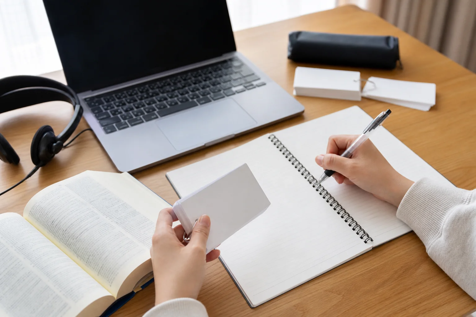 英語のノートに前置詞とセットの動詞を書き出して覚えている手元